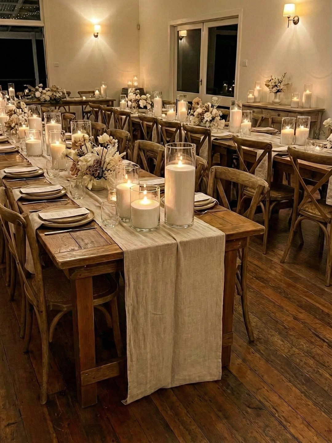 Tall glass candles glowing warmly at a wedding reception